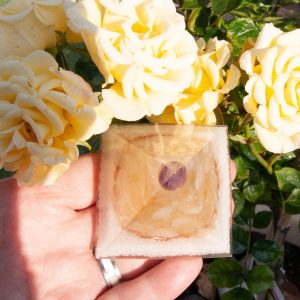 The photograph shows the Citrine resin pyramid on a hand to show size